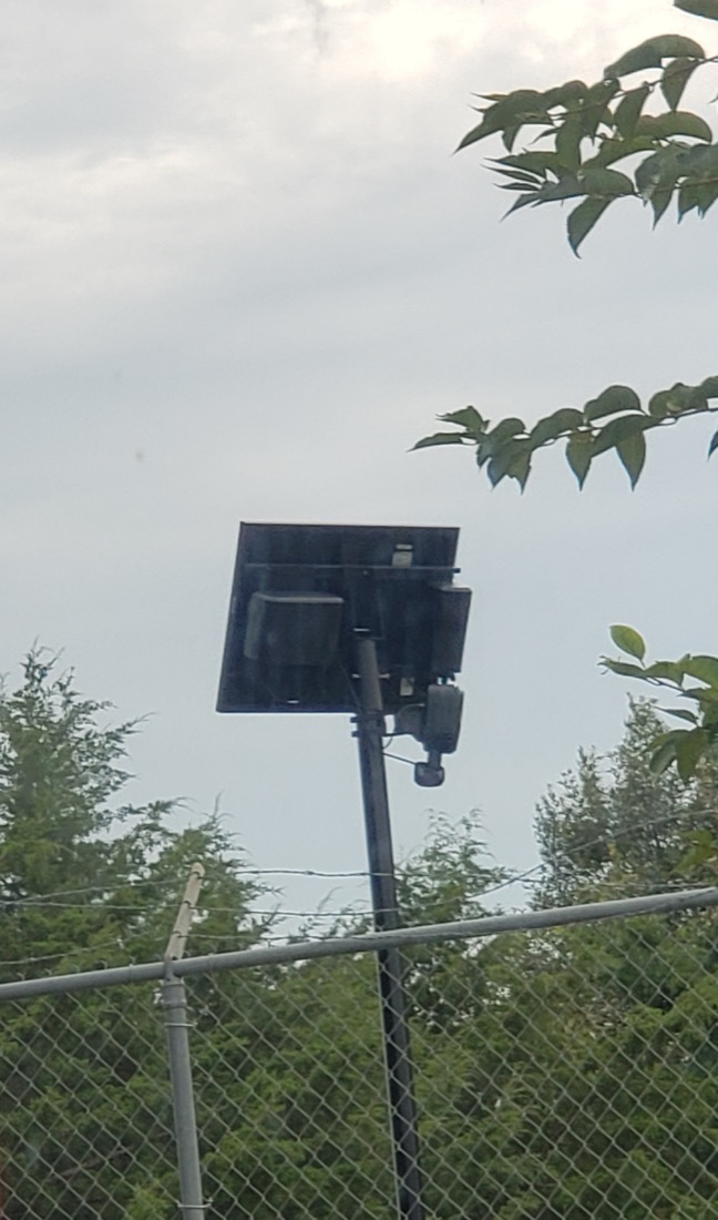 A Flock Safety camera on a thin black pole at a roadside in Hagerstown, Maryland.